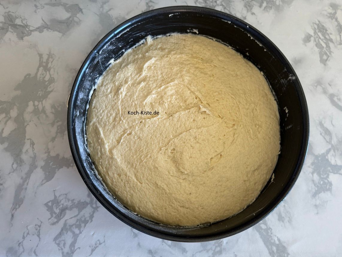 In der Zwischenzeit gebe mit einem Teiglöffel den Teig in die Springform und streiche ihn glatt.