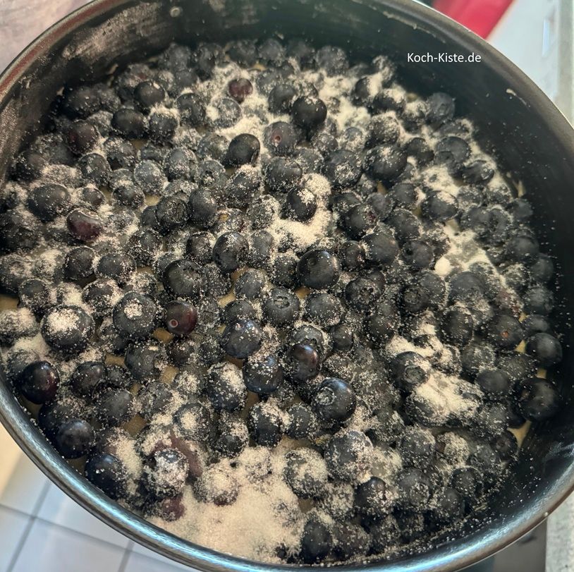 Vor dem Backen verteile noch 2 Esslöffel Zucker gleichmäßig auf den Blaubeer Kuchen.