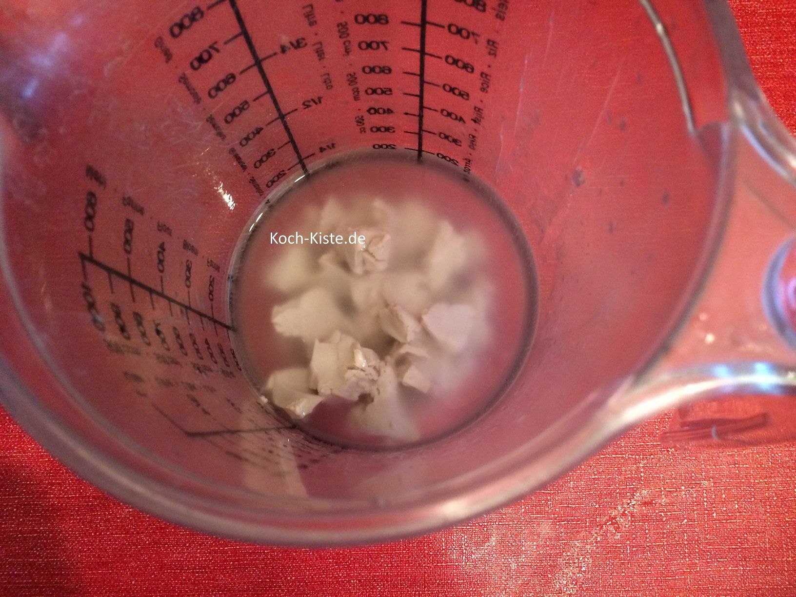 In die abgemessene Wassermenge die Hefe hinein bröckeln und mit dem Schneebesen so lange rühren, bis sich die Hefe ganz aufgelöst hat.