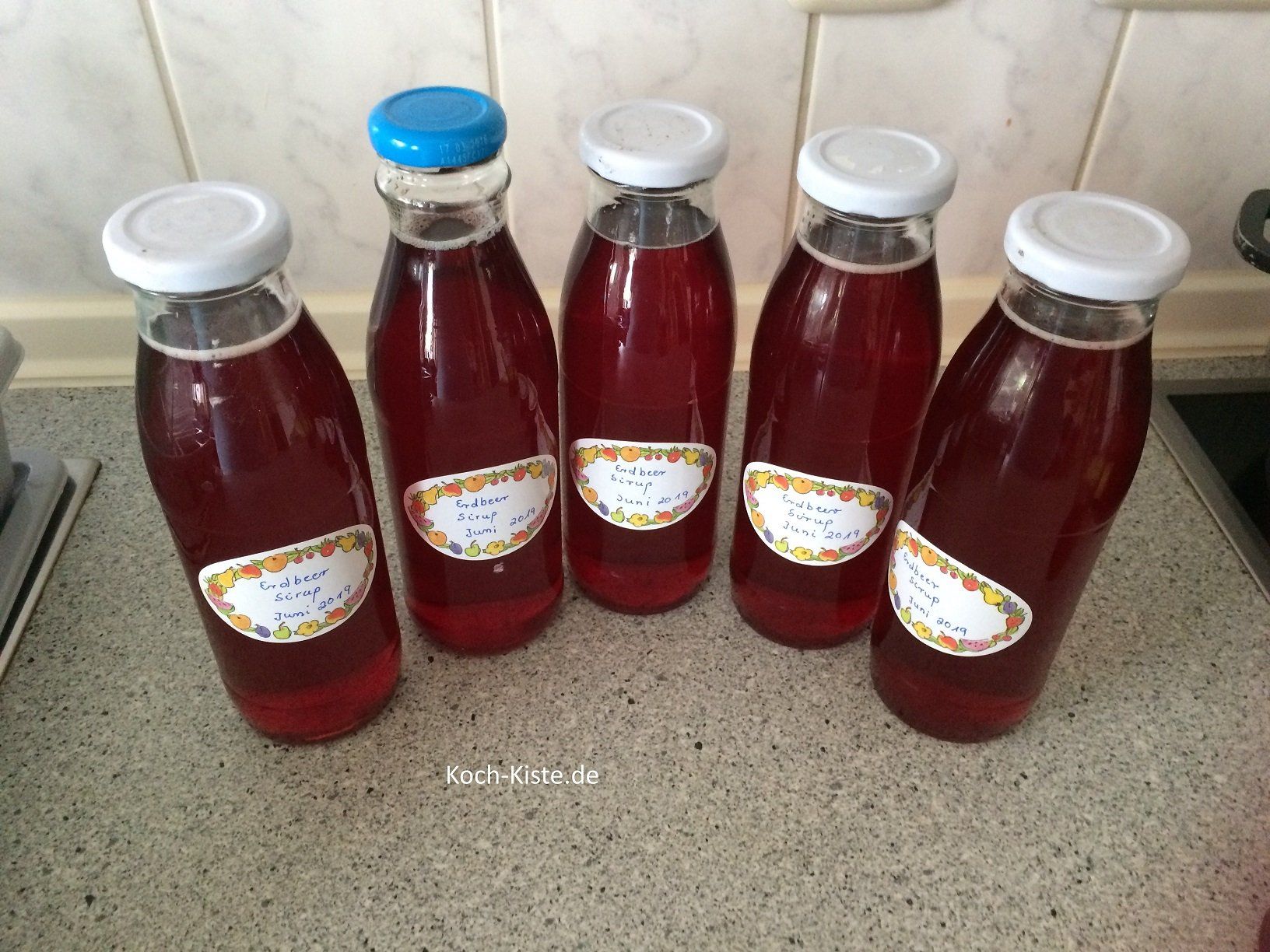 Erdbeer-Sirup in die vorbereiteten Flaschen füllen