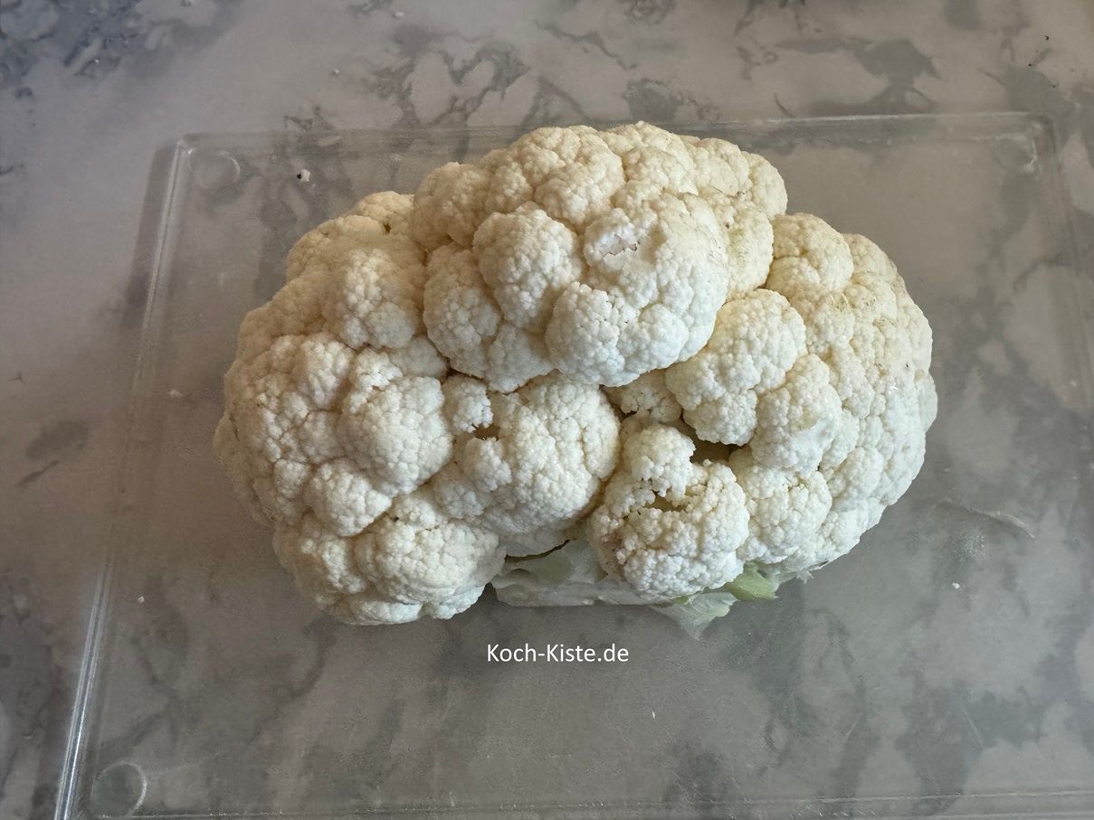 Lege Dir den Blumenkohl auf das Schneidebrett und entferne mit einem Messer die Blattansätze. Dann teile den Blumenkohl in Rößchen
