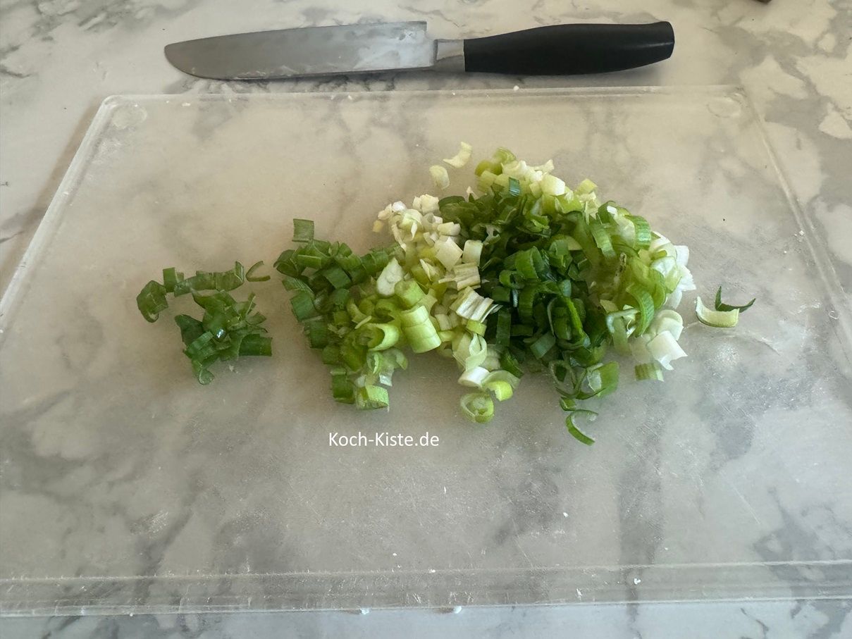 halbiere die Lauchzwiebel und schneide sie dann in kleine Stücke. Die Schritte wiederholst Du auch bei den anderen Lauchzwiebeln.