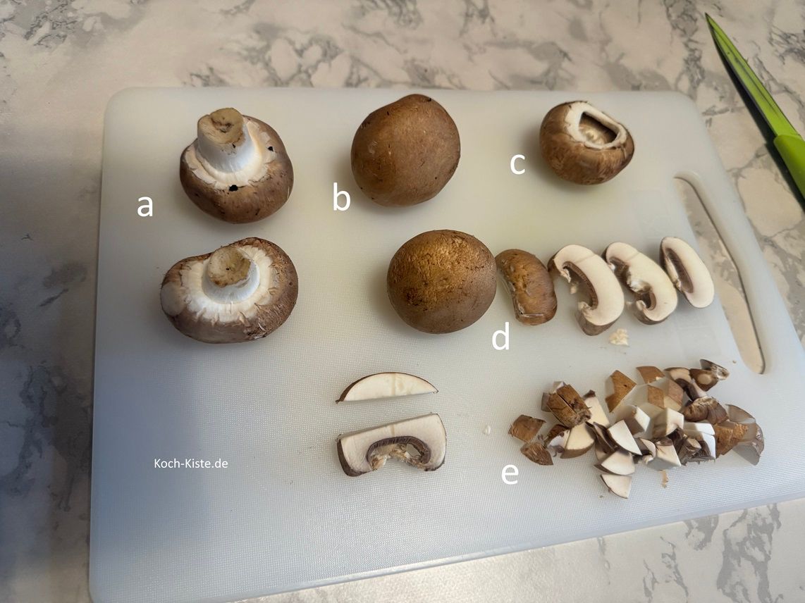 beginne damit jeden Champi auf das Schneidebrett zu legen (a) und mit Küchenpapier Unreinheiten abzuwischen. (b) Dann breche auf der Unterseite den Pilzfuß heraus(c) , schneide den Champi in Scheiben (d) und dann in kleine Stücke (e)