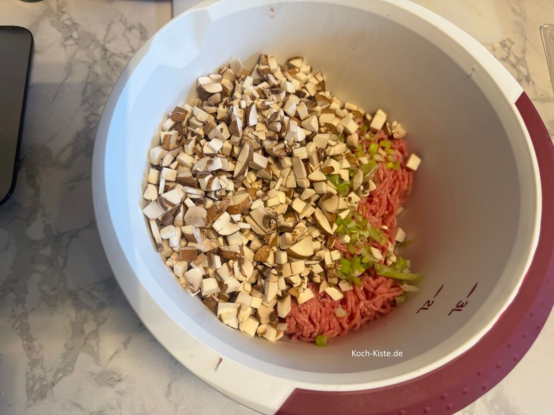 Gebe das Hackfleisch, die Gewürze, die Lauchzwiebeln und Pilzstücke in eine Rührschüssel