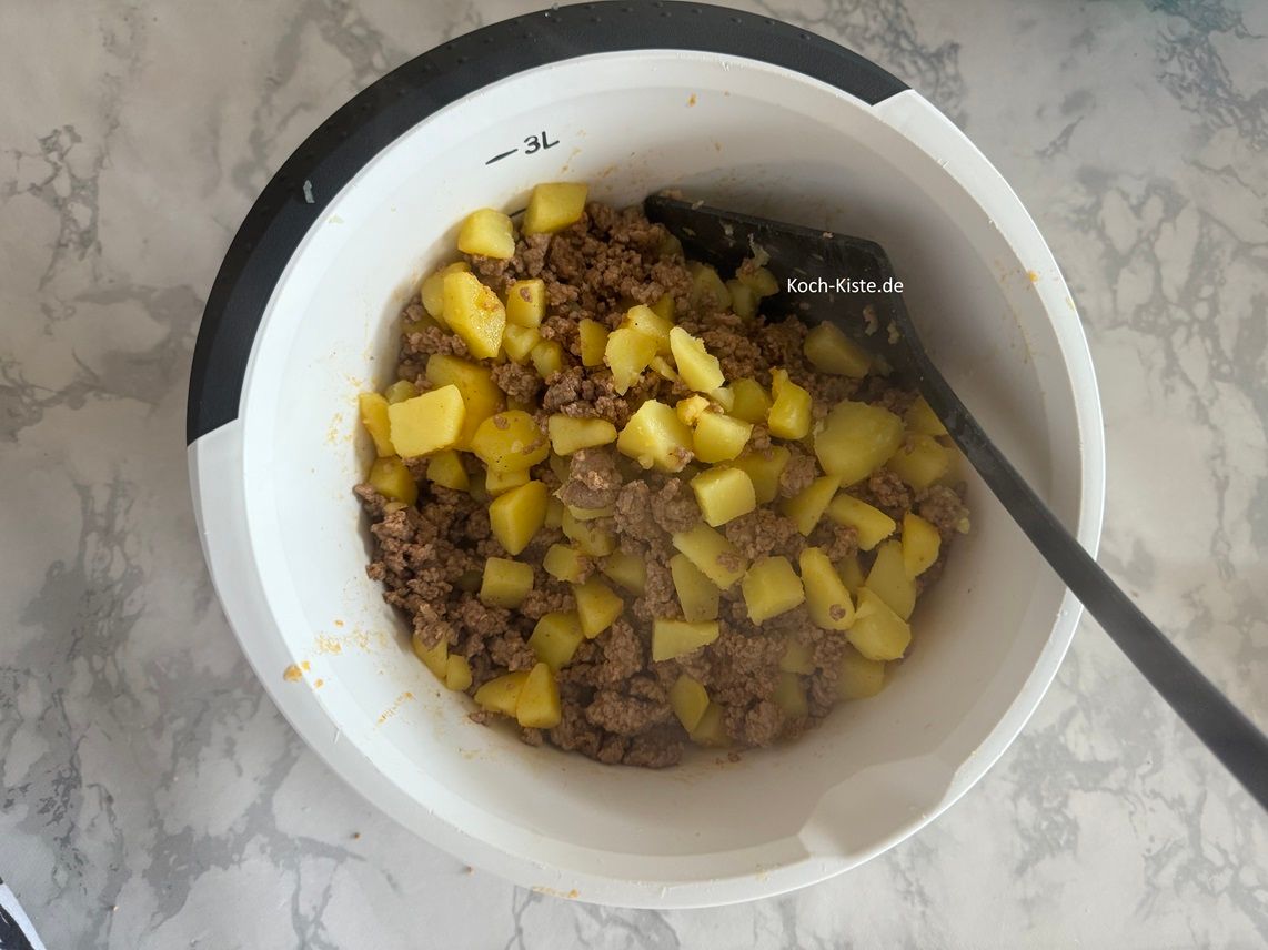 schütte die Kartoffelstücke mit in die Rührschüssel und vermenge beides gut miteinander. Nun kannst Du die Hack-Kartoffelmasse in eine Auflaufform schütten.