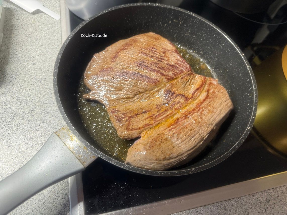 wende den Hirschbraten mit Hilfe einer Fleischgabel und eines Pfannenwenders und brate auch diese Seite 4 Mintuen an