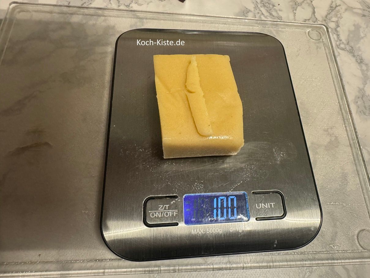 nehme die Marzipanrohmasse aus der Verpackung und halbiere sie. Danach kontrolliere auf der Küchenwaage das Gewicht. Es sollen 100 g sein.