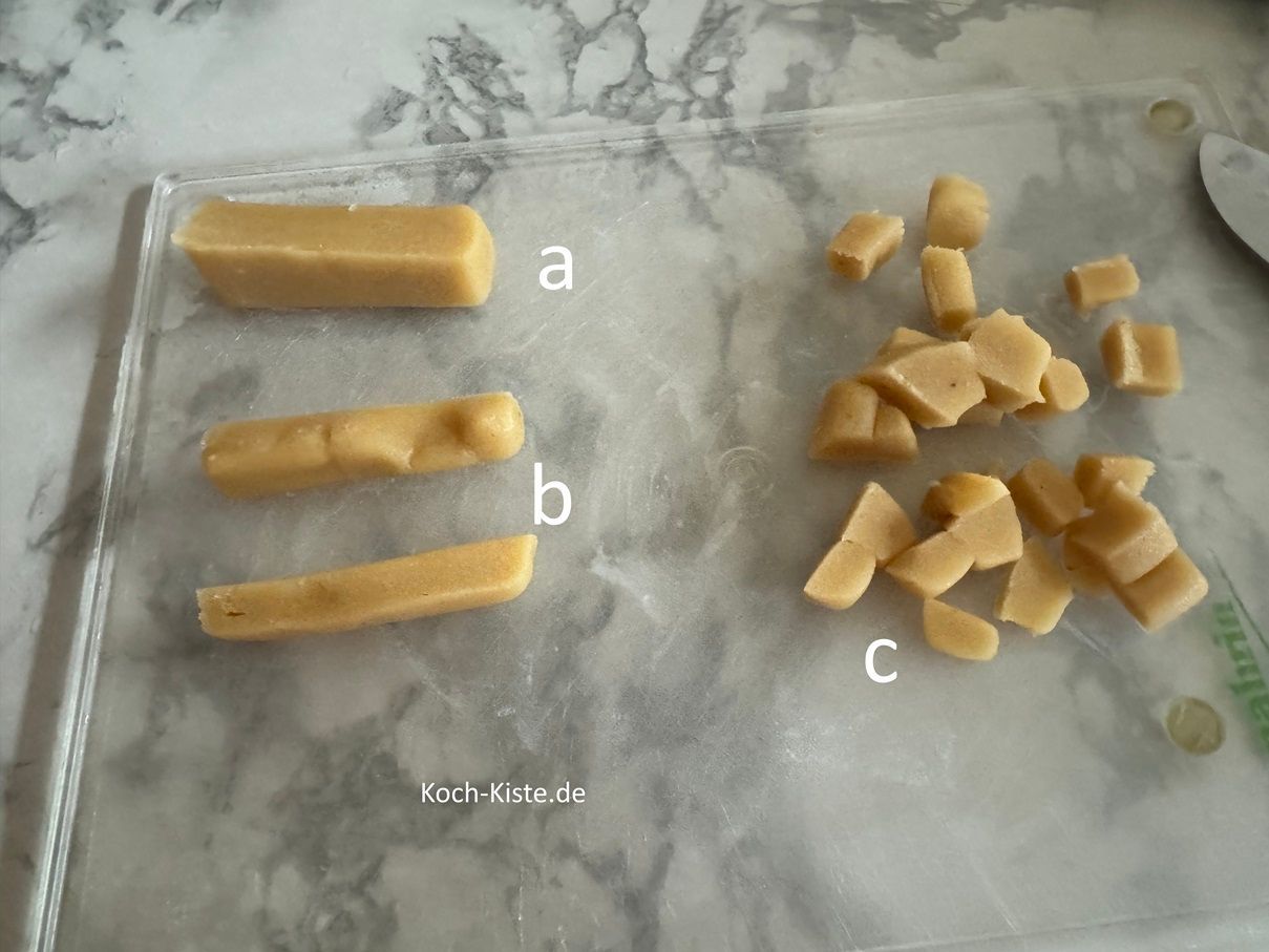 als nächstes wiege Dir 100 g Marzipanrohmasse ab, schneide sie in Scheiben (a), dann in Streifen (b) und in kleine Stücke c)