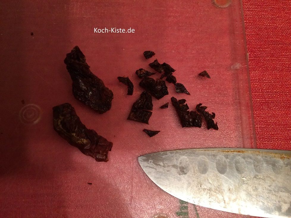 beginne damit die getrockneten Tomaten nacheinander auf das Schneidebrett zu legen und in kleine Stücke zu schneiden