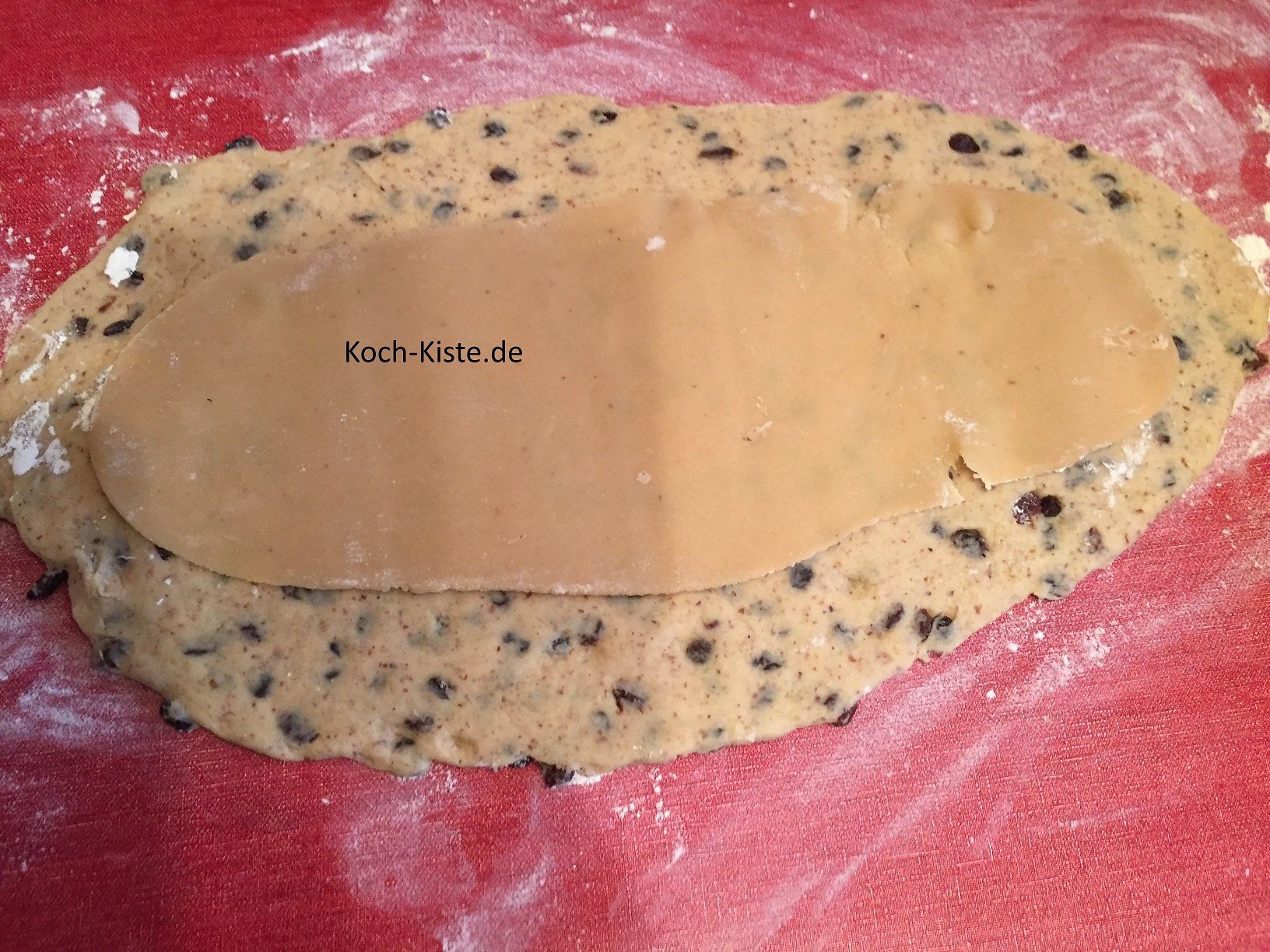 hebe die ausgerollte Marzipan-Rohmasse vorsichtig hoch und lege sie auf die ausgerollte Teigmasse