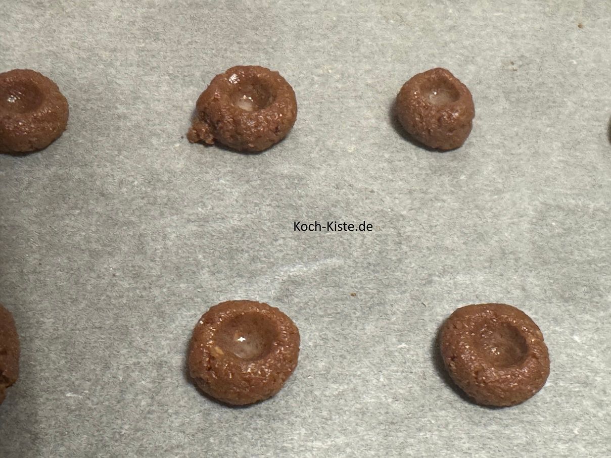als nächstes nimmst Du den Stiel eines Kochlöffels und drückst vorsichtig in jede Teigkugel eine Vertiefung. Achte darauf das Du nicht zuviel Druck ausübst und die Teigkugel dadurch reißt.