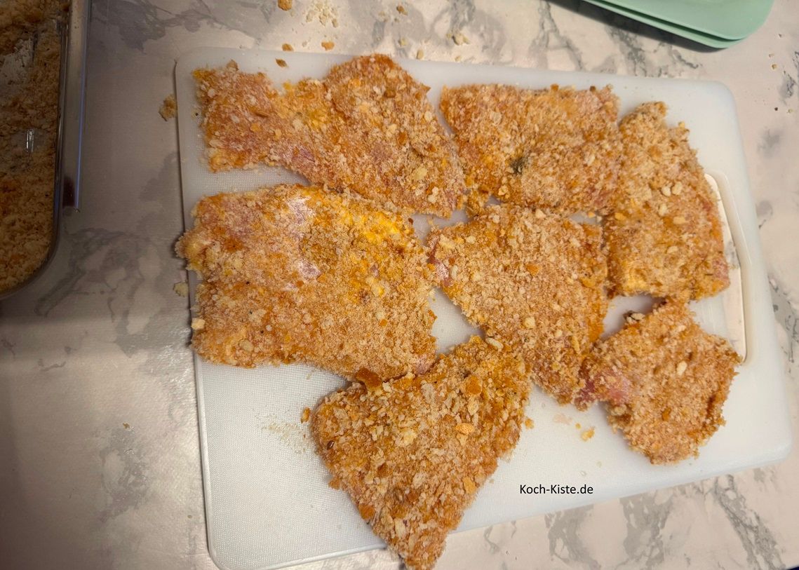 lege die fertig panierten Schnitzelstücke auf ein Schneidebrett