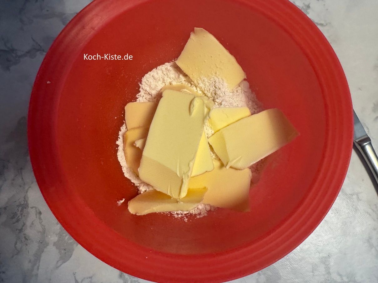 stelle die Küchenwaage ein letztes Mal auf 0 und schubse mit einem Messer 90 g kalte Butter ! mit in die Schüssel. Dann werden die Zutaten zügig mit den Händen verknetet - das Streusel entstehen.
