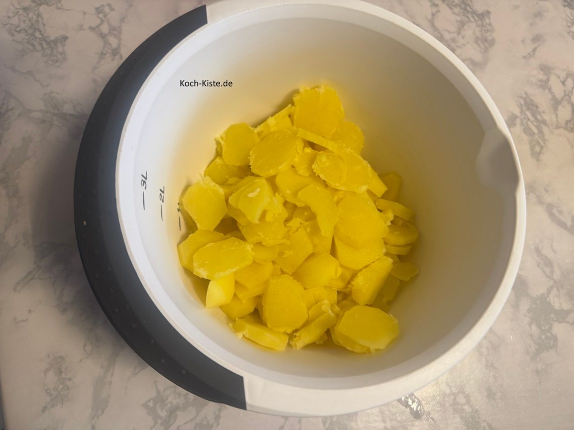 Nehme Dir eine Kartoffel, halte sie über die Rührschüssel und schneide sie in Scheiben. Wiederhole das mit allen Kartoffeln