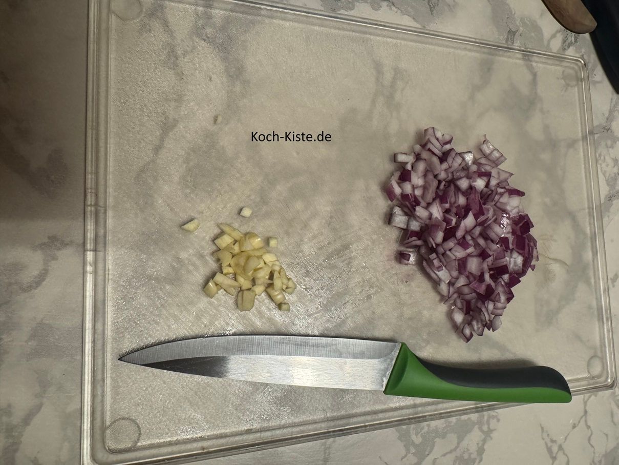 Beginne damit die Zwiebel zu pellen und klein zu schneiden. Dann wiederhole die Arbeitsschritte bei der Knobizehe