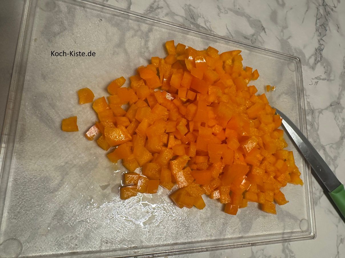 lege die Paprikaviertel wieder auf das Schneidebrett, schneide sie in Streifen und dann in kleine Stücke