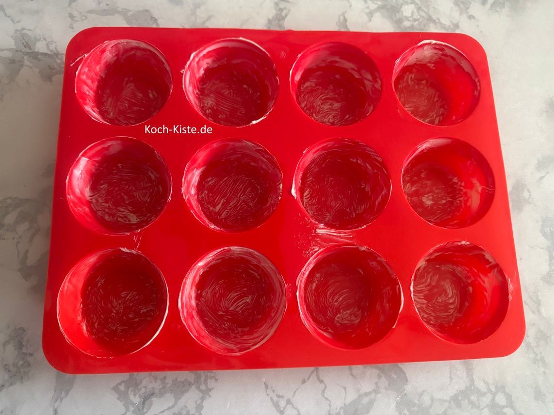 nehme Dir die Muffin Form und fette sie mit Hilfe eines Silikonpinsels, mit weicher Butter ein
