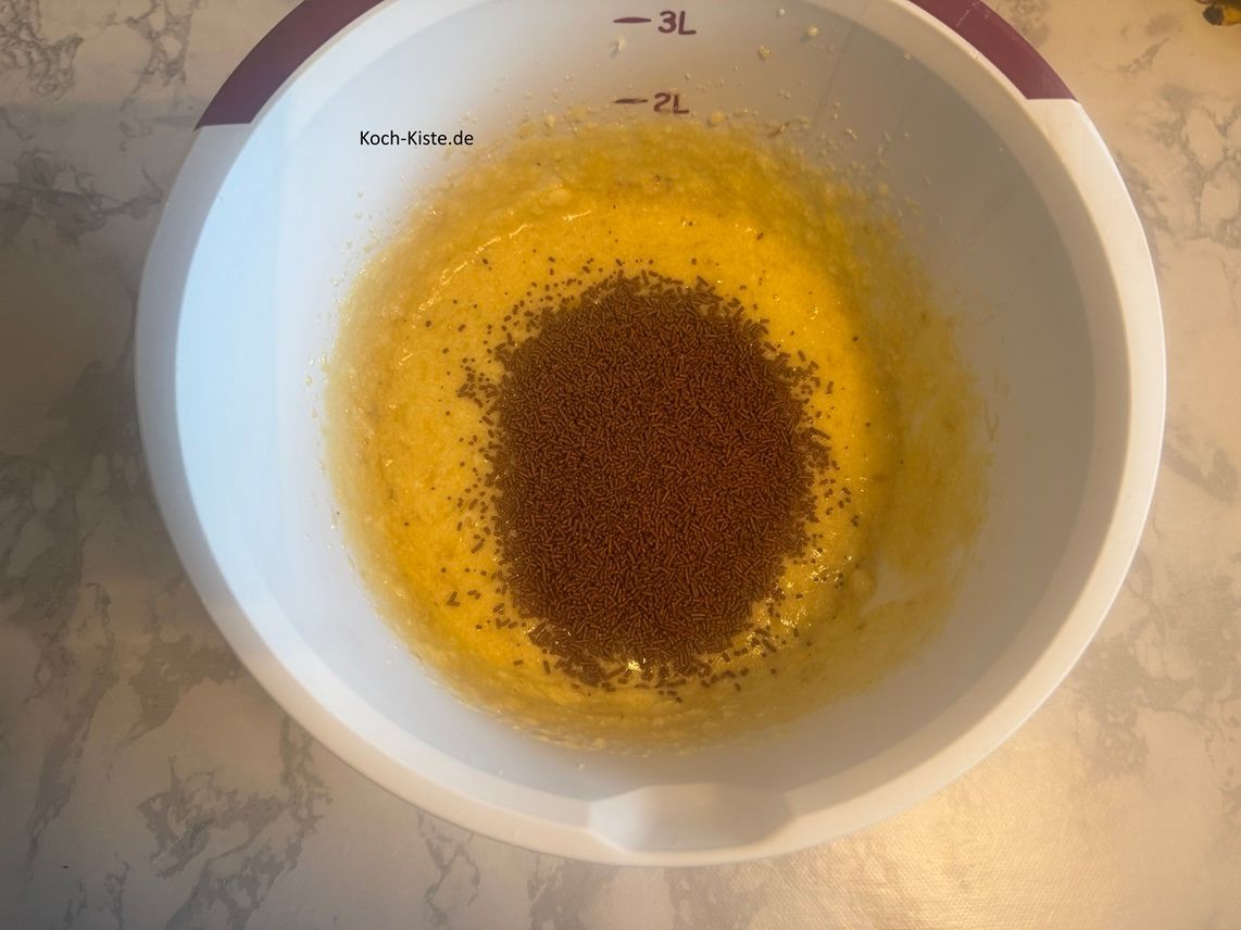 Stelle die Rührschüssel erneut auf die Küchenwaage auf 0 - und wiege 100 g Schokostreusel hinein