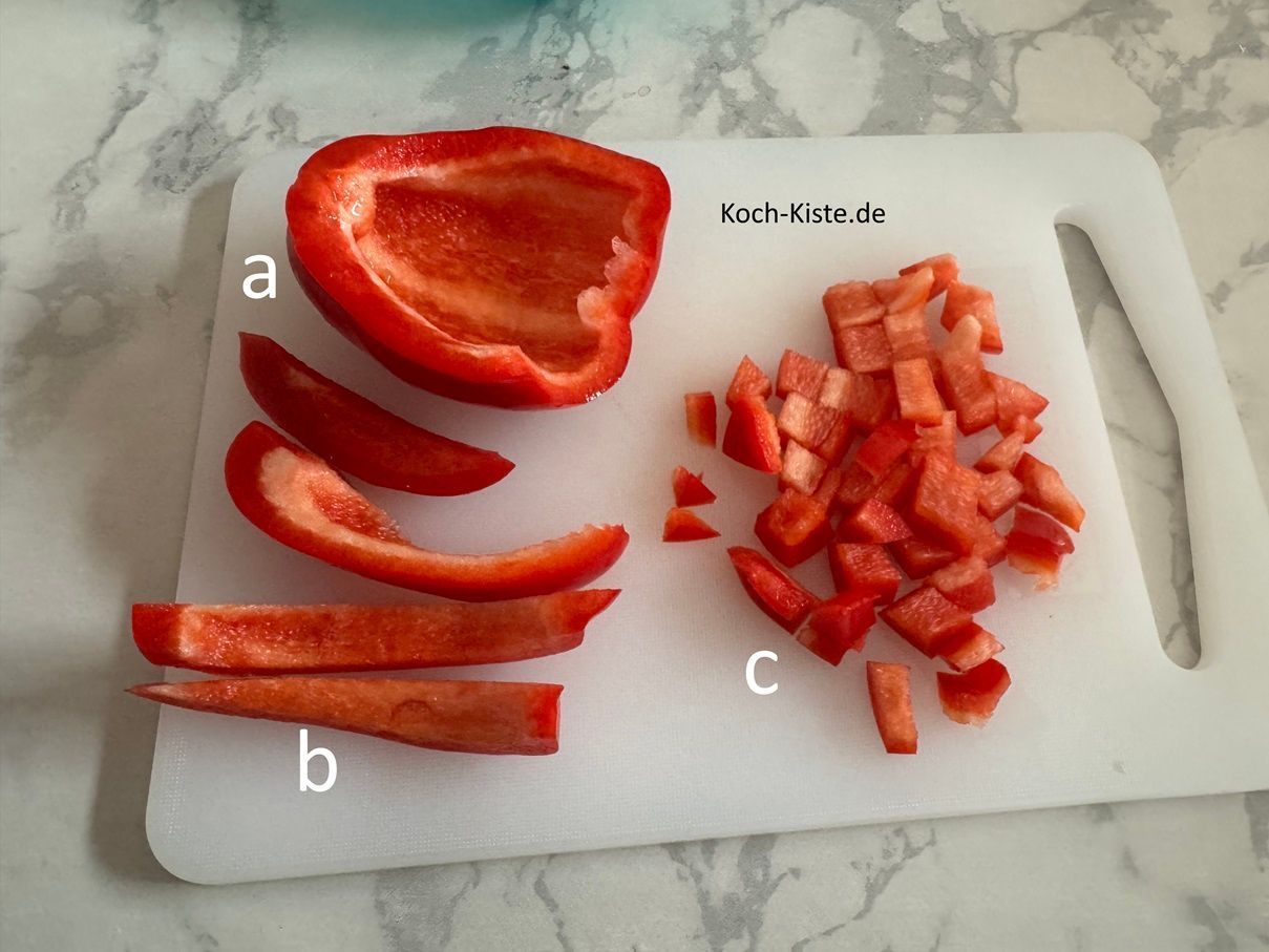 dann spüle die Paprikavierel unter kaltem, fließende, Wasser ab . Lege ein Papirkaviertel wieder auf das Schneidebrett (a) , schneide es in Streifen (b) und dann in kleine Stücke (c)