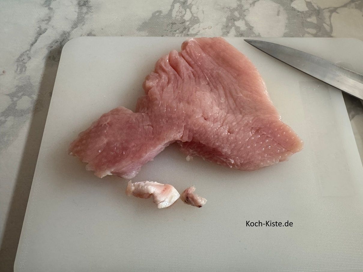 spüle die Putenschnitzel unter kaltem, fließendem Wasser ab und tupfe sie mit Küchenpapier etwas trocken. Dann lege 1 Putenschnitzel auf das Schneidebrett und entferne eventuell vorhandende Sehnen / Fettstücke