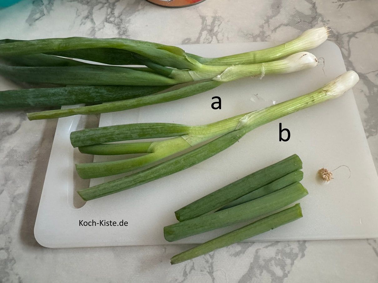 lege 3 Lauchzwiebeln auf das Schneidebrett (a) , entferne die Wurzelstücke (b) und oben was vom Grünen (c)