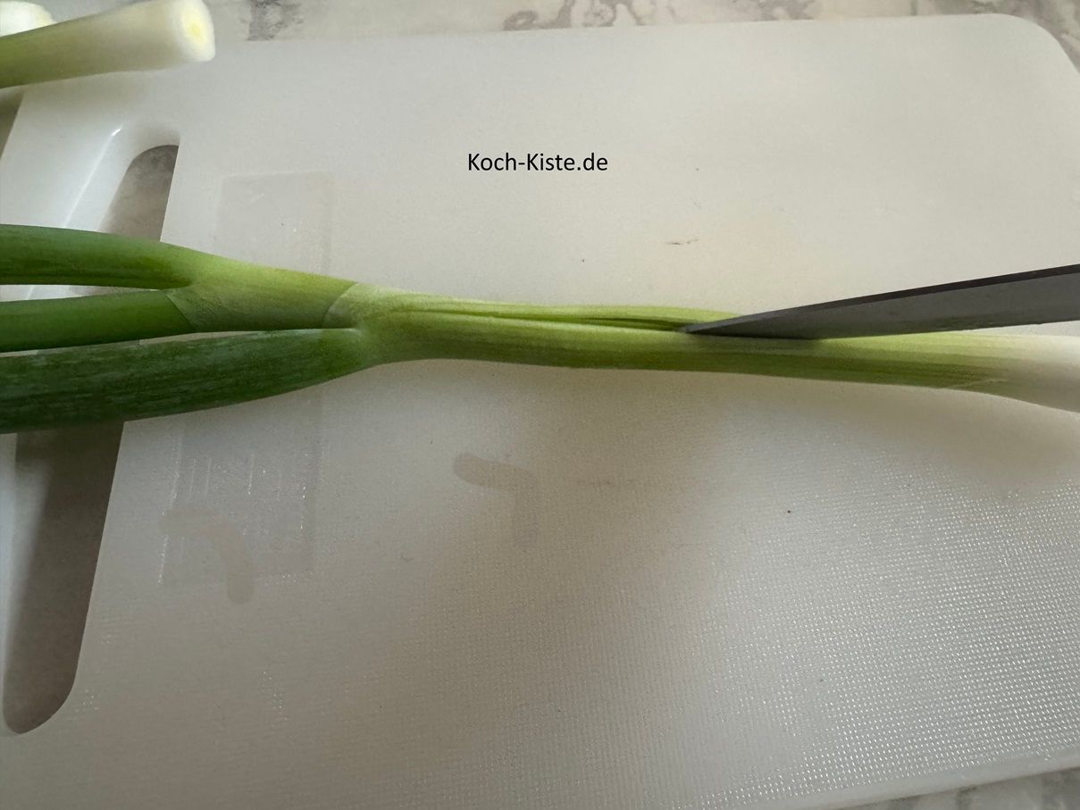 lege 1 Lauchzwiebel auf das Schneidebrett und trenne sie waagerecht