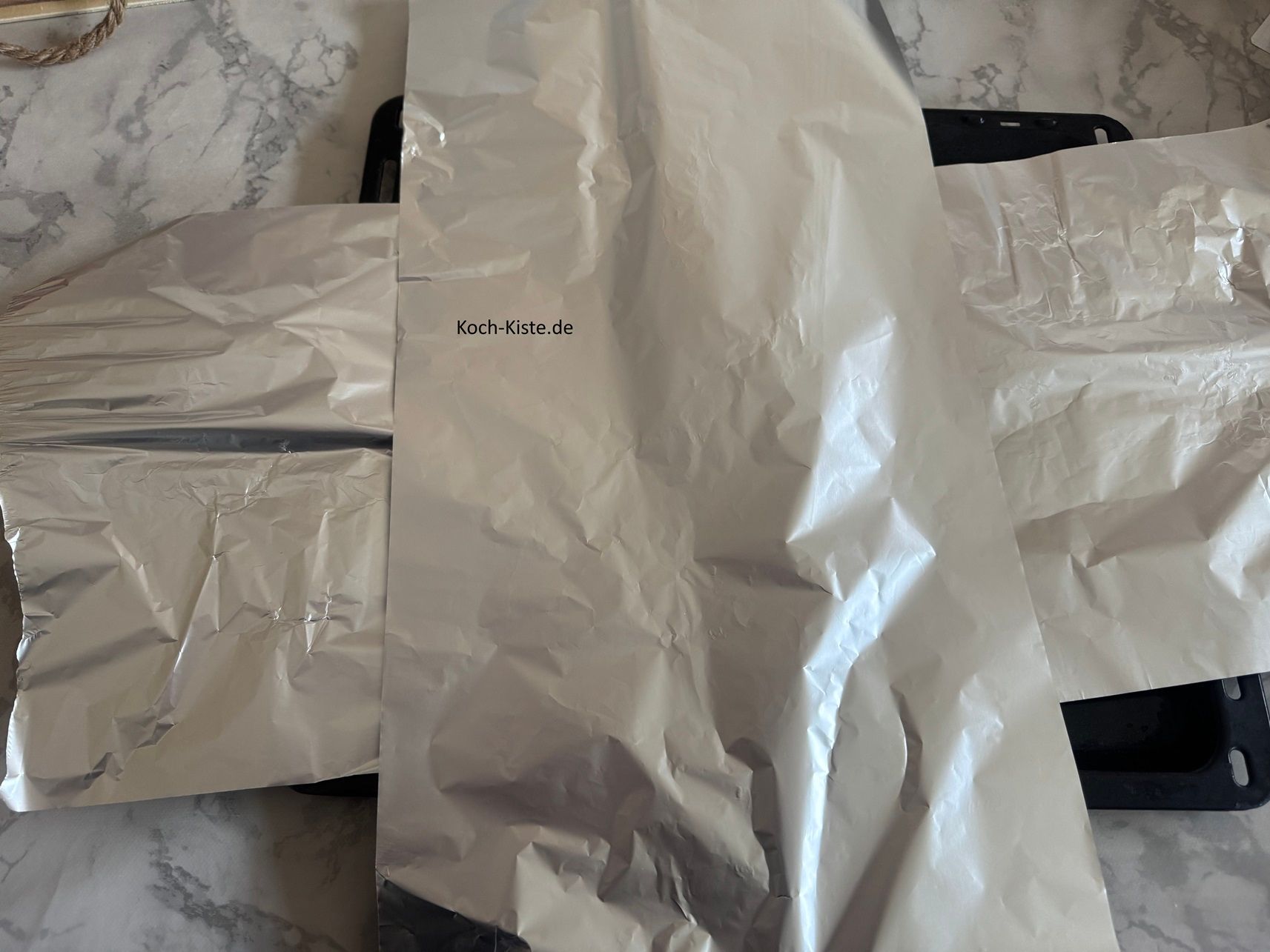 lege Dir 1 Stück Alufolie quer und 1 Stück Alufolie hochkant auf das Backblech
