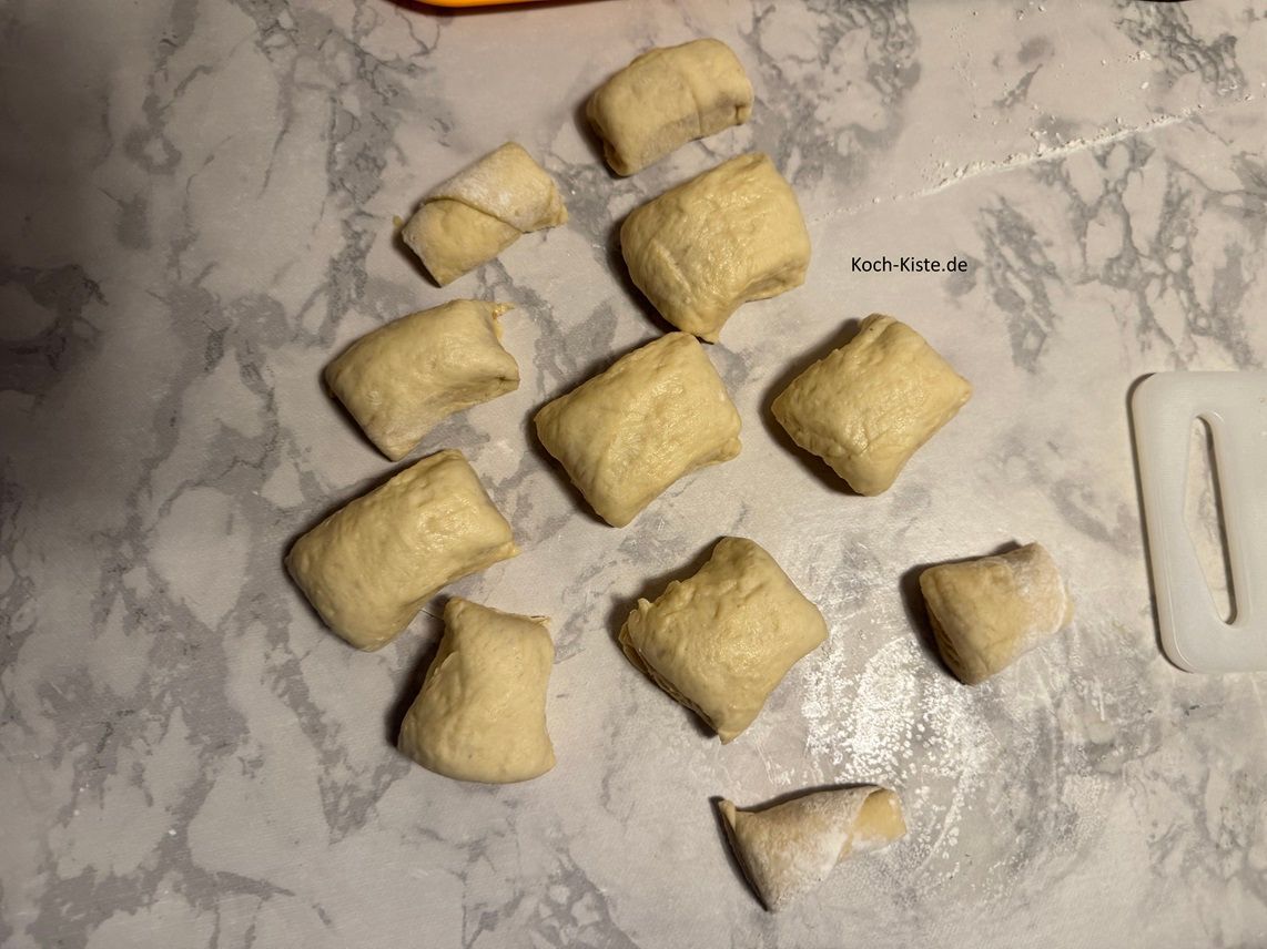 Als nächstes lege ein kleines Schneidebrett unter einen Teil der Teigrolle und schneide ca. 5 cm lange Teigstücke ab. Wiederhole den Schritt bis die gesamte Teigrolle in Stücke geschnitten ist