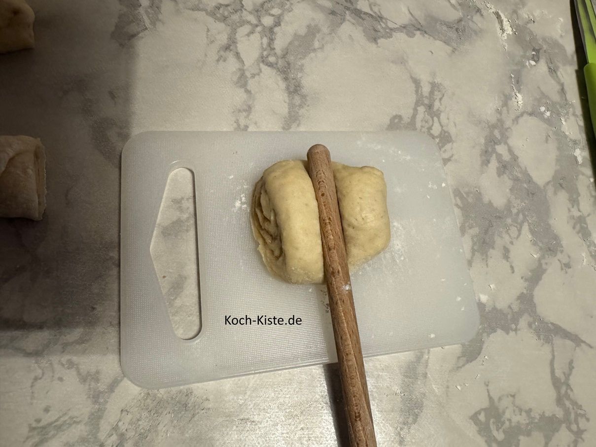damit die Franzbrötchen die typische Form bekommen: lege 1 Stück Teig vor Dich mit den offenen Stellen zur Seite. Dann nehme einen Holzkochlöffelstiel und drücke diesen in die Mitte auf dem Teig- so dass, der Teig an der Stelle flach wird. Nun drücke den Teig von den offenen Seitem her - über die flache Stelle zusammen. Endspurt: lege die Teiglinge auf das Backblech, bestreiche sie mit Milch und backe die Franzbrötchen für ca. 15 Minuten bis sie eine schöne Farbe angenommen haben.
