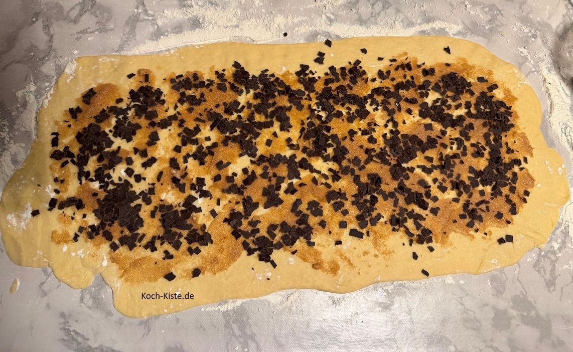 Schoko Franzbrötchen: wenn Du die Butter-Zimtmischumg auf den Teig aufgetragen hast, werden noch 40 g Schokoraspel gleichmäßig auf dem Teig verteilt.