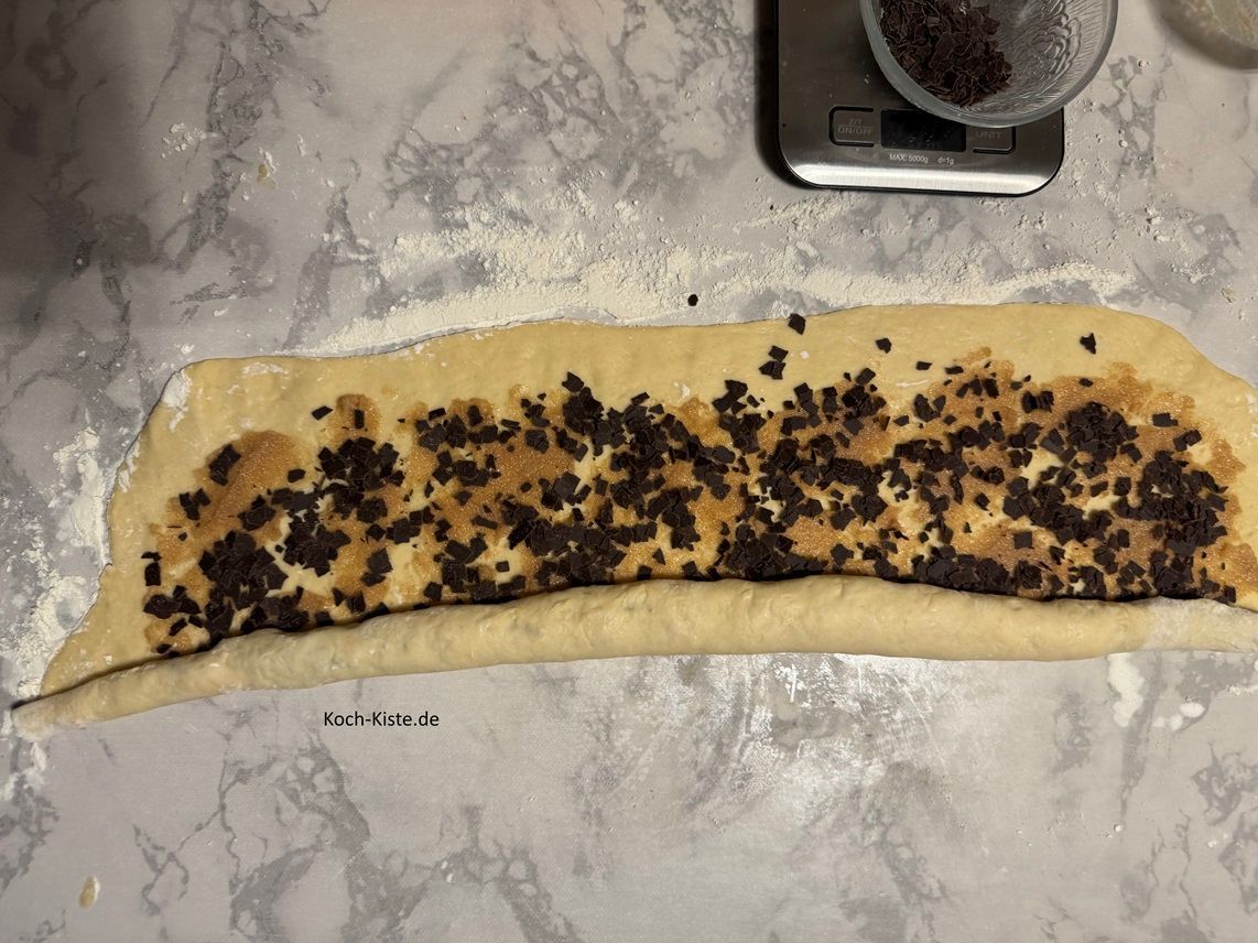 rolle den Schoko Franbrötchenteig genauso zusammem, schneide ihn in ca. 5 cm lange Teigteile, lege sie auf das Backblech, bestreiche die Teigteile mit Milch und verteile 20 g Schokoraspel auf die Teiglinge. Dann backe die Schoko Franzbrötchen auch ca. 15 Minutem bis sie gold-braun sind,