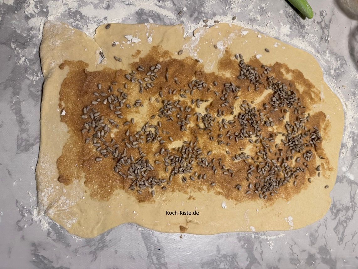 Sonnenblumenkerne Franzbrötchen : verteile 35 g Sonnenblumemkerne auf die Butter - Zimtmischung. Rolle dem Teig auf , schneide ihn in ca. 5 cm lange Stücke. Forme die Franzbrötchen, lege sie auf das Backblech , streiche sie mit Milch ein und vertieile die restlichen 25 g Sonnenblumenkerne oben auf dem Teiglingen.