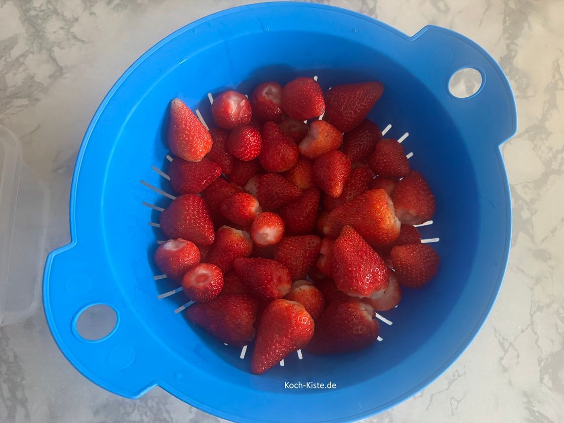 entferne bei den Erdbeerenkelch und gebe die Erdbeeren in ein Küchensieb. Spüle die Erdbeeren unter kaltem, fließendem Wasser ab.