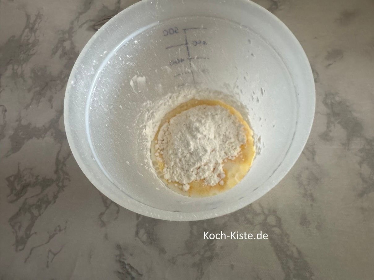 In der Zwischenzeit gebe die 2 Päckchen Vanillepuddingpulver und 4 Esslöffel Zucker mit in den Messbecher.