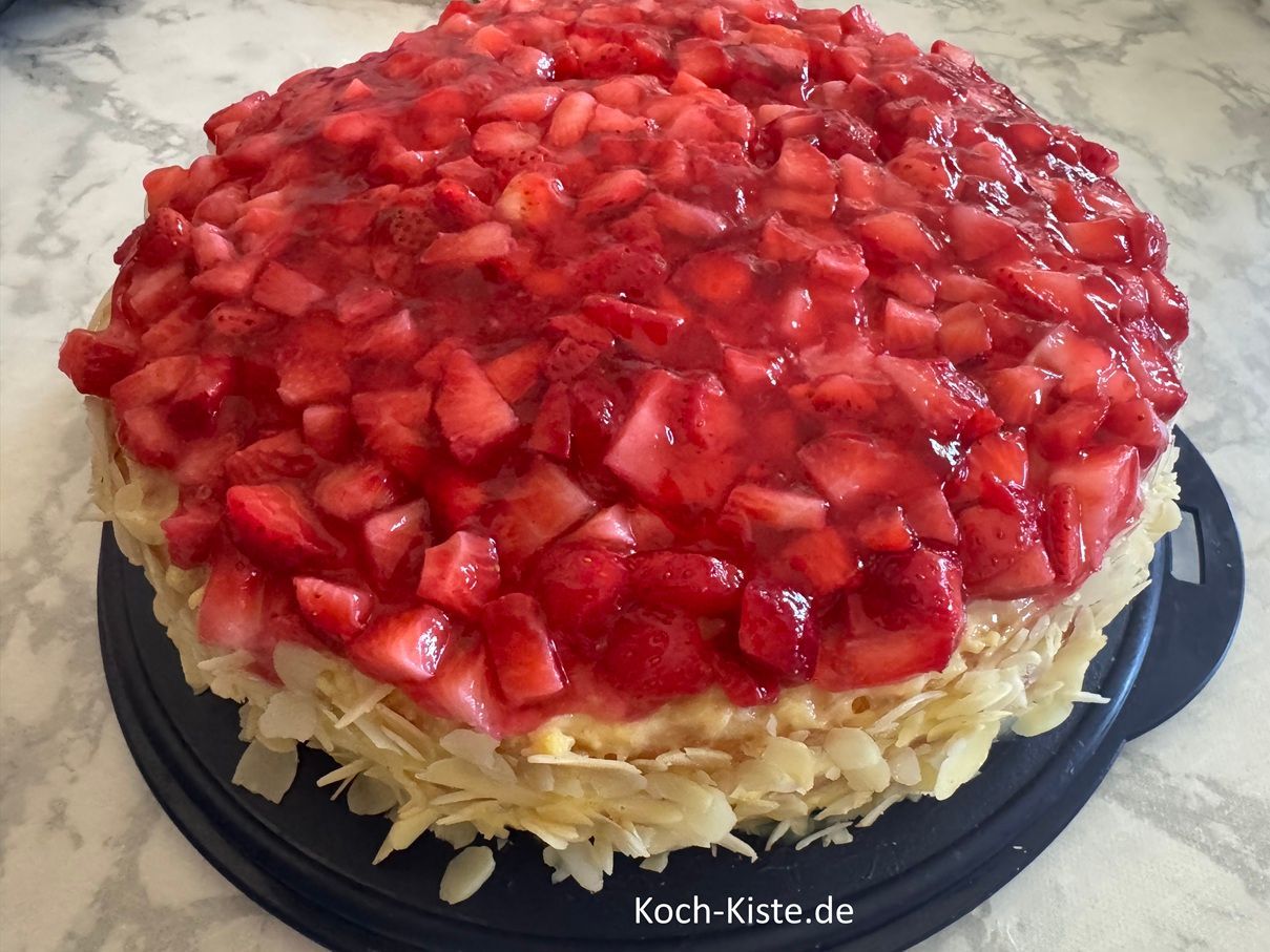 jetzt kommen die Mandeln dran. Nehme Dir immer ein paar gehobelte Mandeln in die Hand und drücke mit Daumen, Zeigefinger - und Mittelfinger der anderen Hand die Mandeln an den Tortenrand.Wiederhole den Vorgang bis die ganze Torte mit Mandel belegt ist.