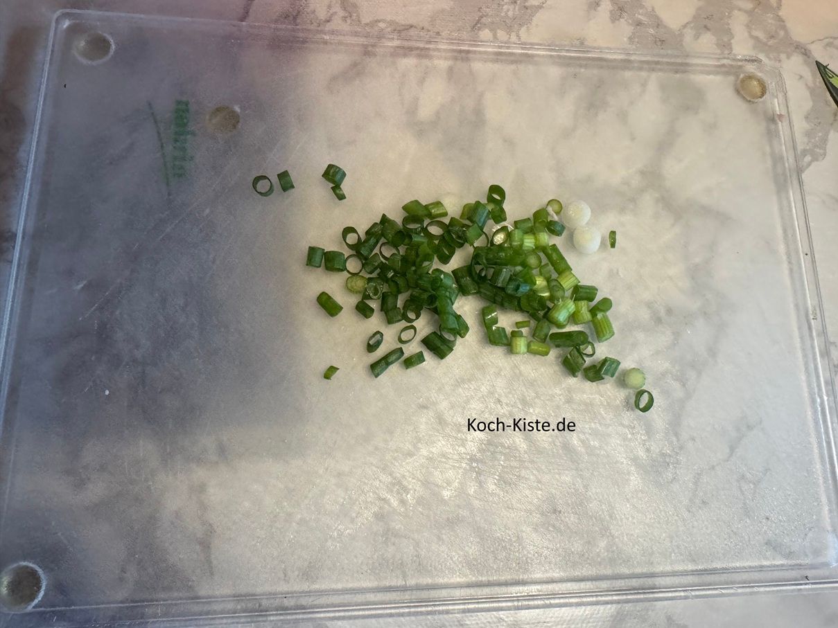 entferne von der Lauchzwiebel oben etwas vom Grünen und unten das Wurzelstück Dann schneide die Lauchzwiebel (oben wo das Grüne beginnt) schräge ein und ziehe die äußere Schicht der Lauchzwiebel ab. Jetzt schneide die Lauchzwiebel in kleine Stücke.