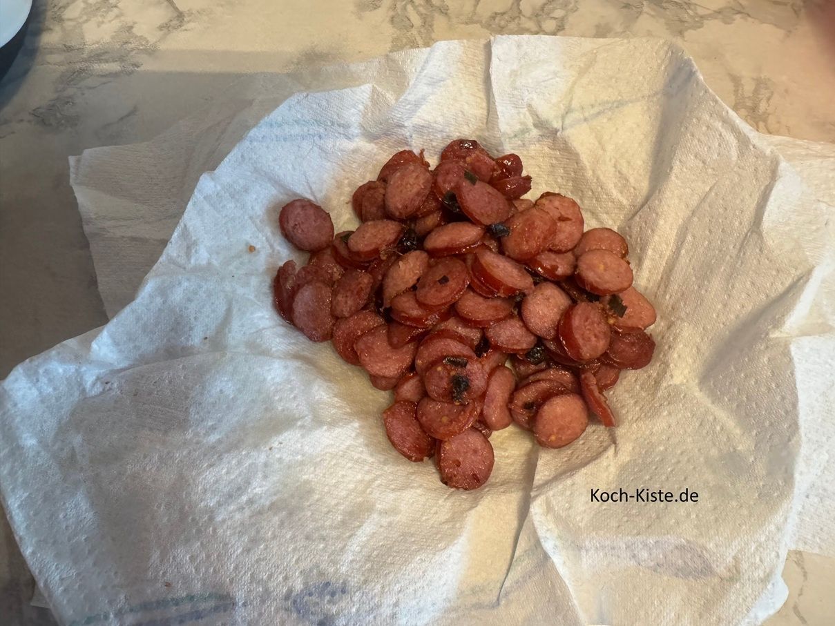 Nun müssten die Mettendenscheiben fertig sein. Lege auf einen tiefen Teller das Küchenpapier, nun gebe die Mettendenscheiben mit Hilfe eines Pfannenwenders auf den Teller. Lasse das Fett für 2 Minuten abtopfen.