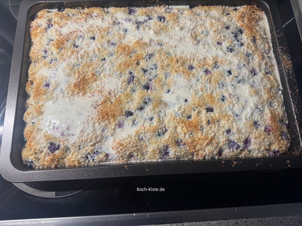 gieße 200 ml frische Sahne gleichmäßig über den ganzen Blaubeer Kokos Kuchen und lasse die Sahne mindestens 1 Stunde lang einziehen.