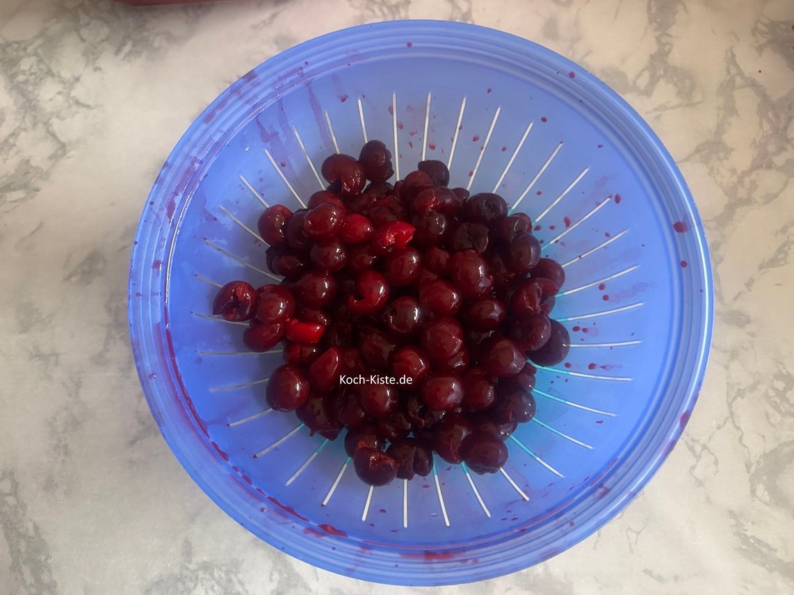 gebt die Sauerkirschen in ein Küchensieb und spült sie unter katlem, fließendem Wasser ab . Dann ernferne die Kirschsrtiele. Nun nehme Dir eine Kirsche und drücke mit dem Daumen leicht oben auf die Stelle wo sonst der Stiel sitzt. Nun kannnst Du den Kirschstein leicht entfernen. Lege die entsteinte Kirsche in die Schale. Wiederhole diese Schriitte bei jeder Kirsche.