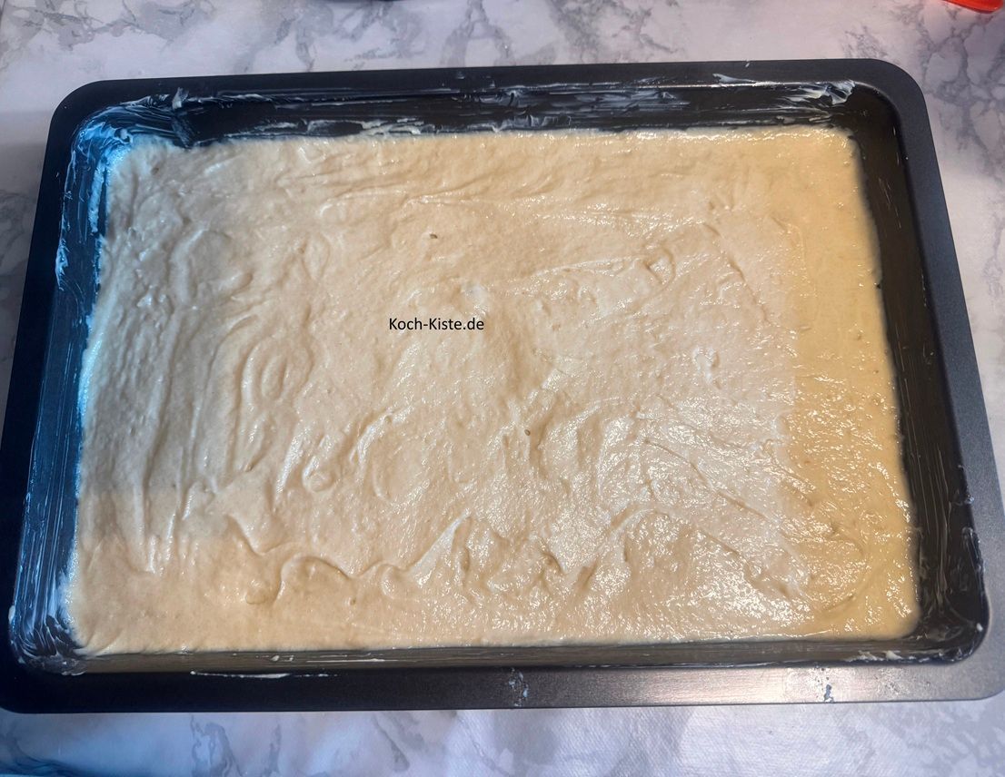 gebe mit einem Teigspatel den Teig auf das Backblech und verteile ihn gleichmäßig. Durch kleine hin-und her Bewegungen mit dem Teigspatel ist es einfacher die Teigoberfläche gleichmäßig hin zu bekommen.