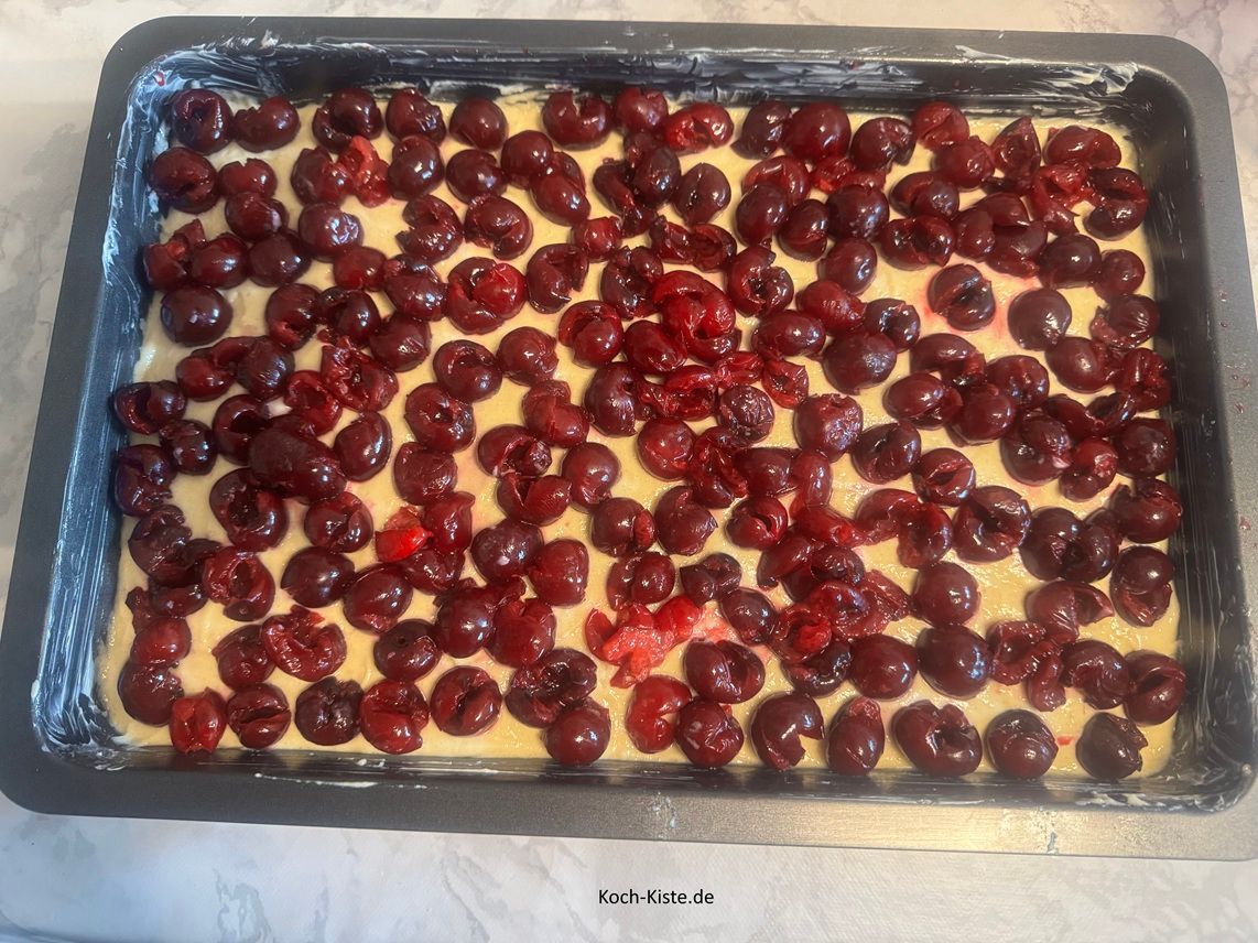 nun kannst Du die Sauerkirschen gleichmäßig auf den Teig verteilen