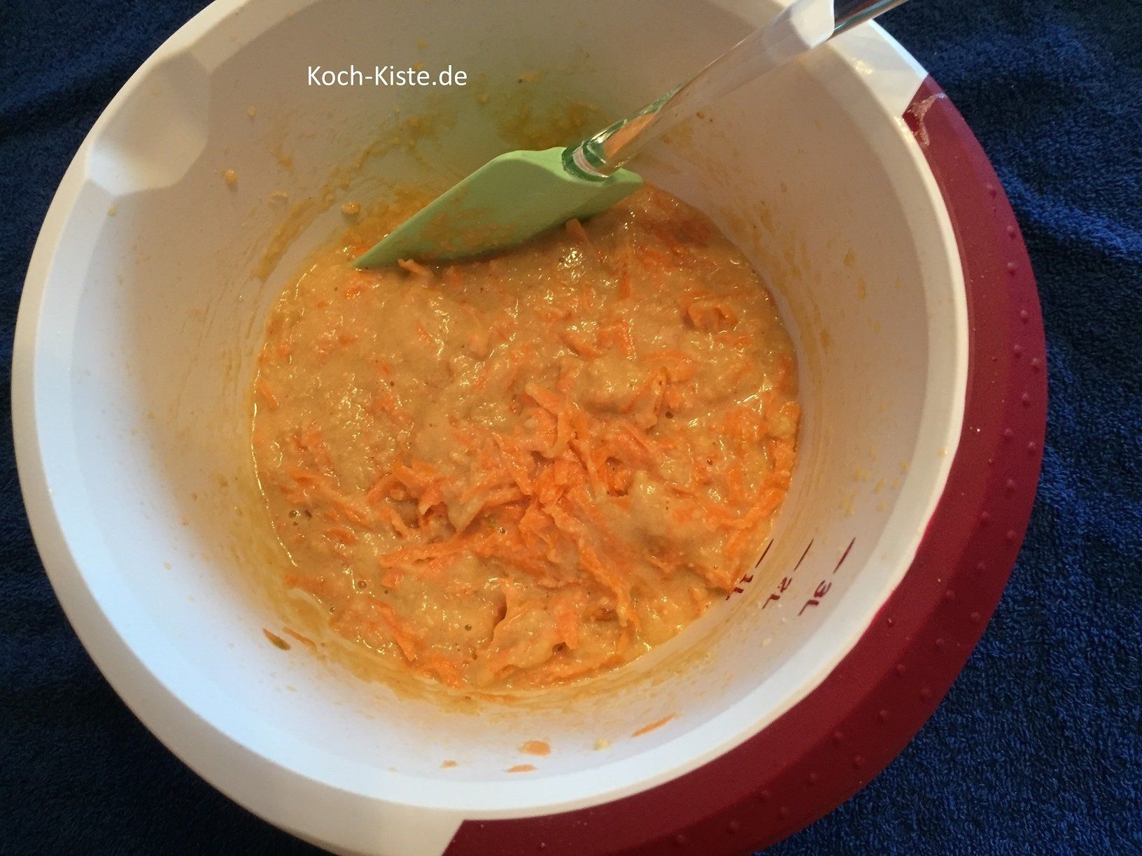 Möhrenraspeln mit einem Teiglöffel unter den Teig rühren