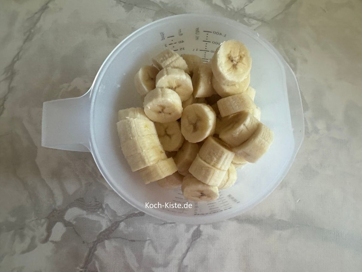 lege die Bananen nacheinader auf das Schneidebrett und schneide sie in Stücke. Gebe die Bananenstücke in einen Messbecher
