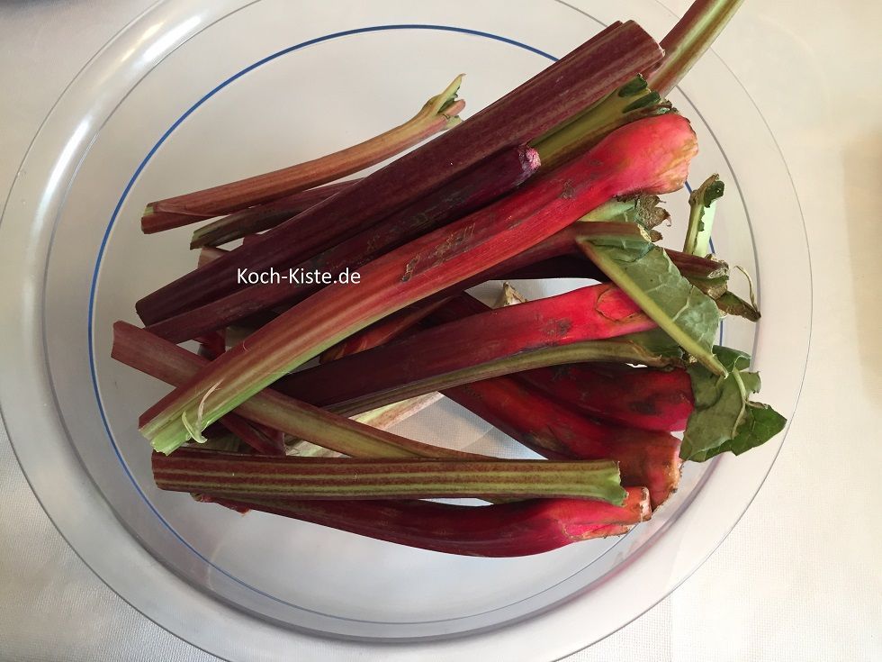 putze den Rhabarber in dem Du bei jeder Stange oben und unten ein Stück entfernst und jede Stange schälst. Danach schneide die Rhabarberstangen in kleine Stücke und gebe sie in ein Küchensieb.