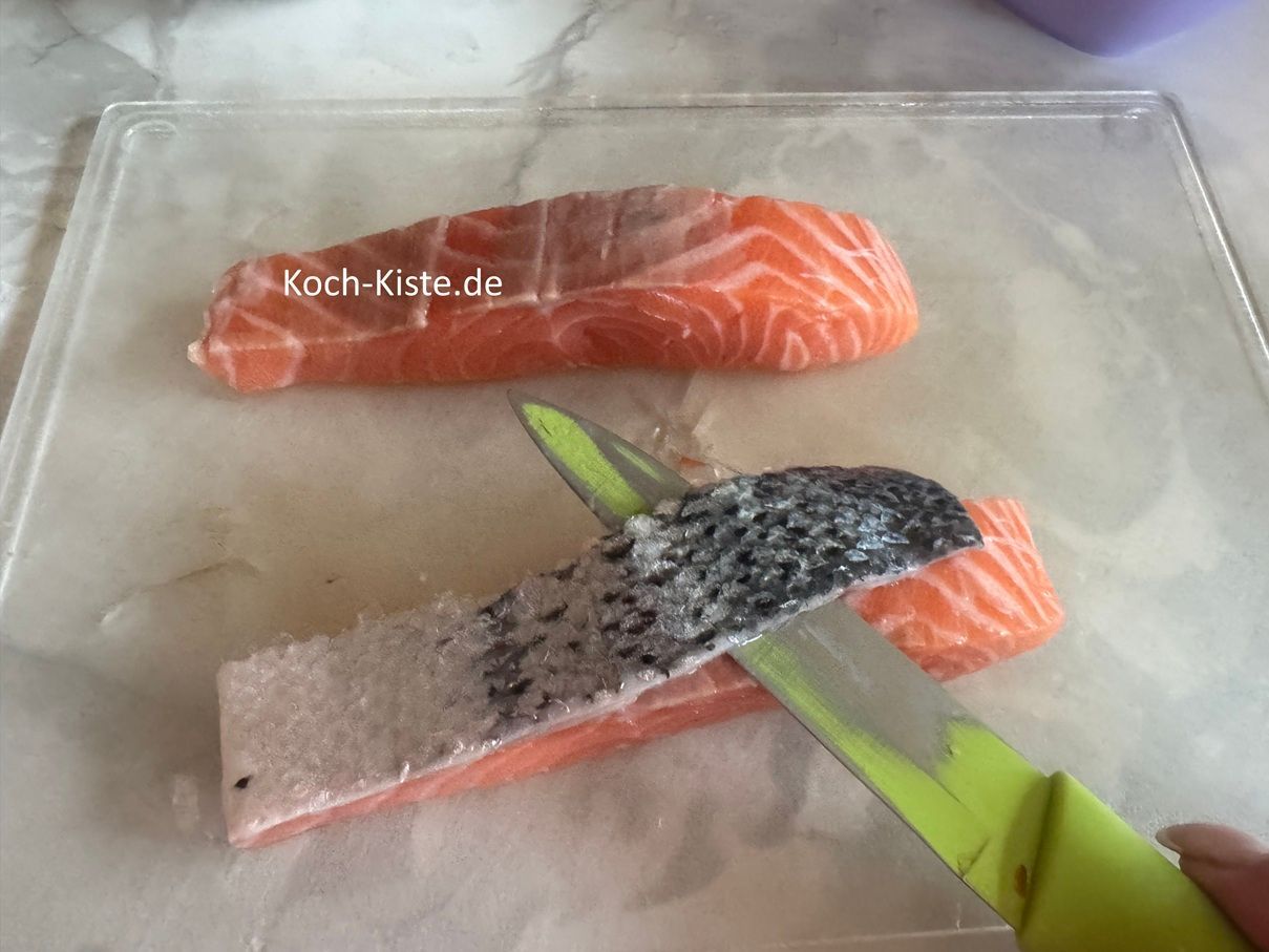 lege 1 abgespültes Lachsfilet auf das Schneidebrett und schiebe das Messer zwischen Haut und Lachsfleisch. Nun entferne die Haut .