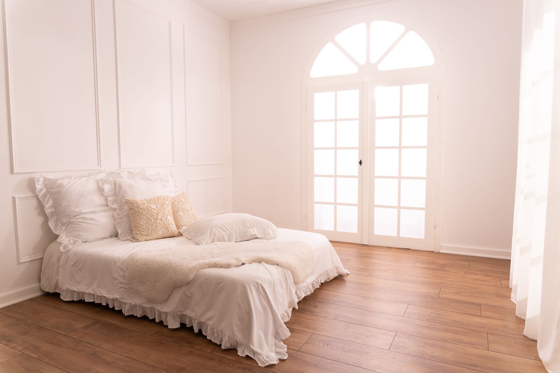 Heller Raum mit weißem Bett und großen Bogenfenstern – luftige und romantische Shooting-Atmosphäre.