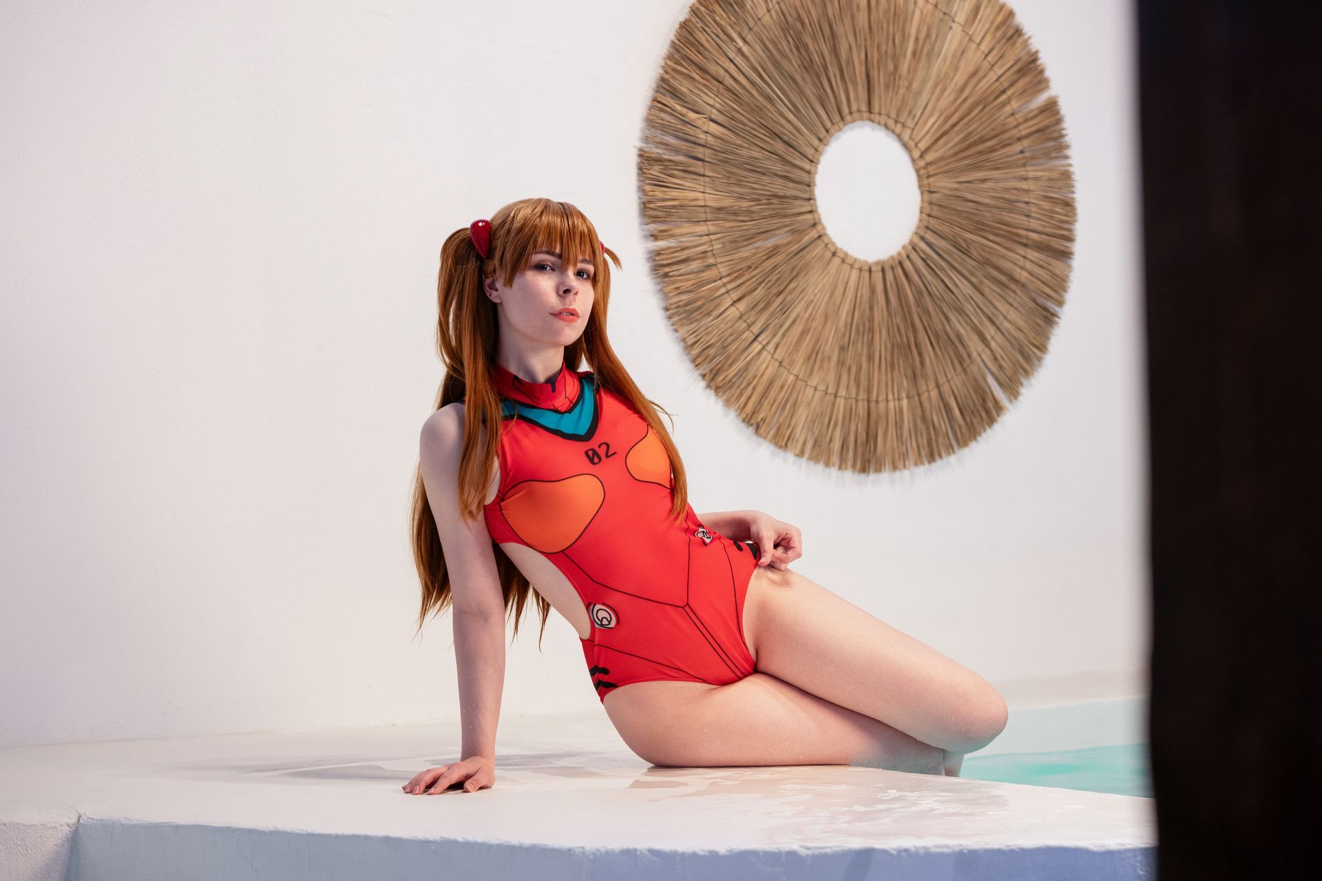 Cosplayerin in rotem Anzug sitzt auf dem Boden neben einer geflochtenen Dekoration