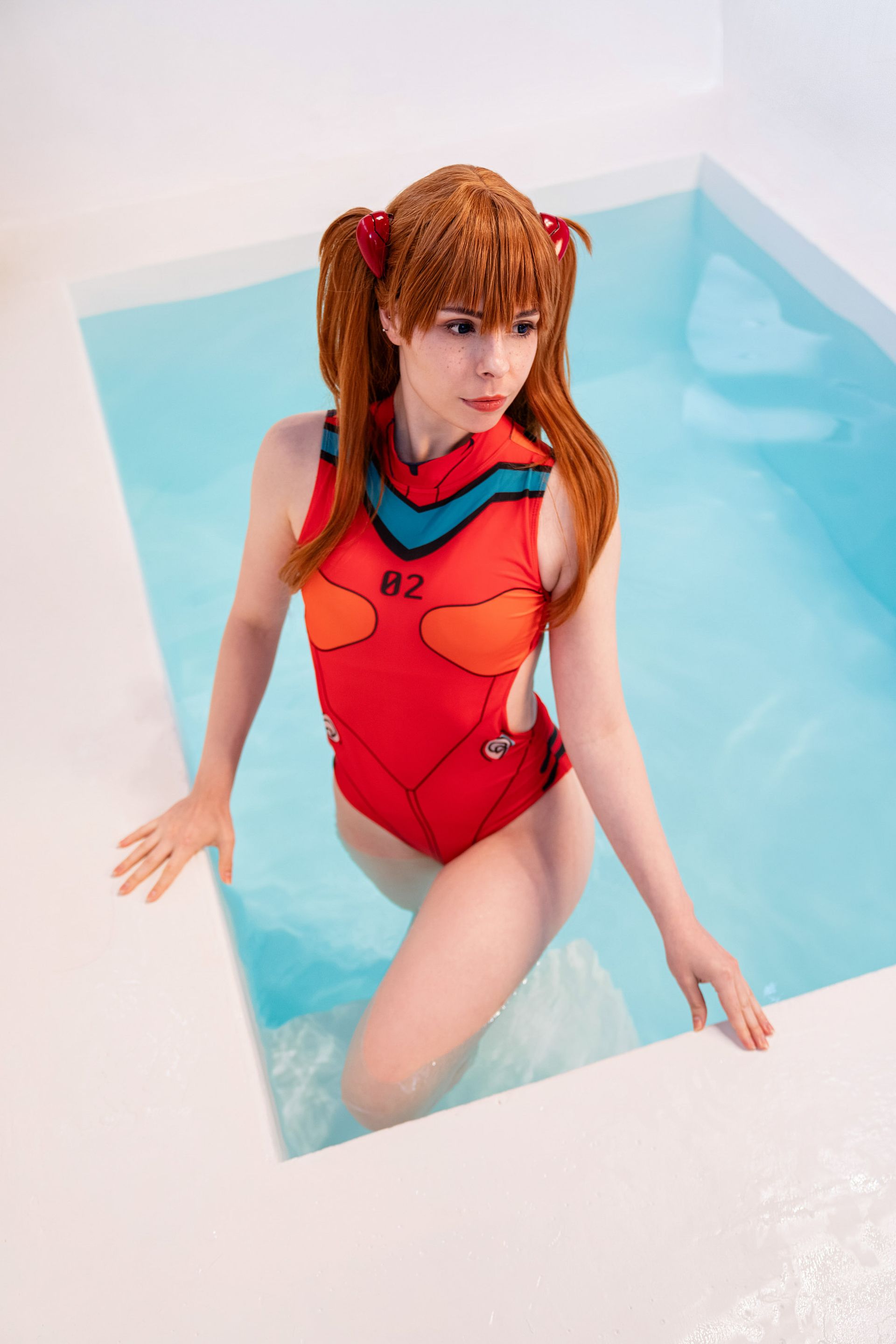 Cosplayerin in rotem Anzug sitzt am Pool und schaut in die Kamera