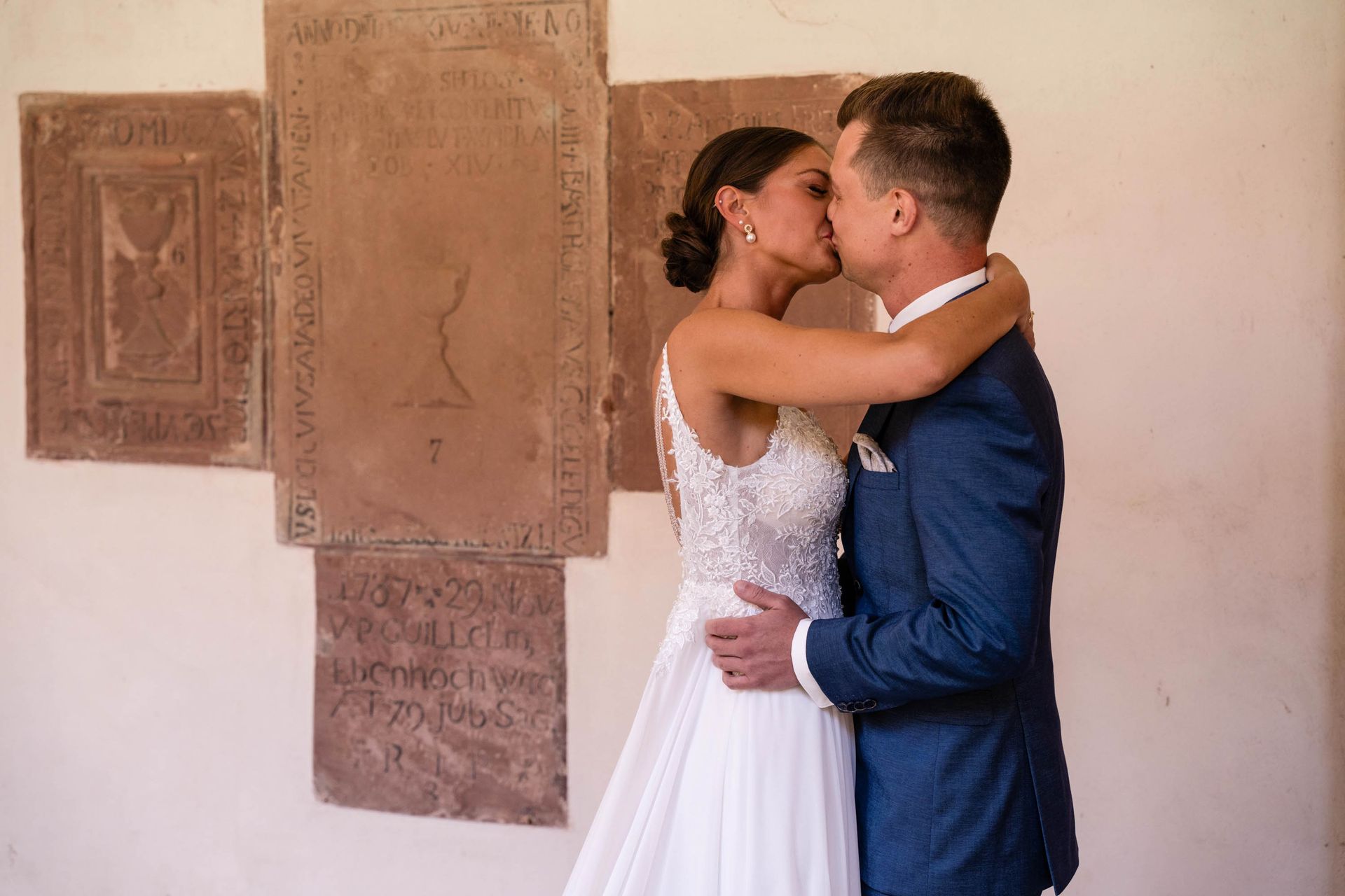 First Look im Kreuzgang Kloster Bronnbach, Braut ist beim Bräutigam und er küsst sie.