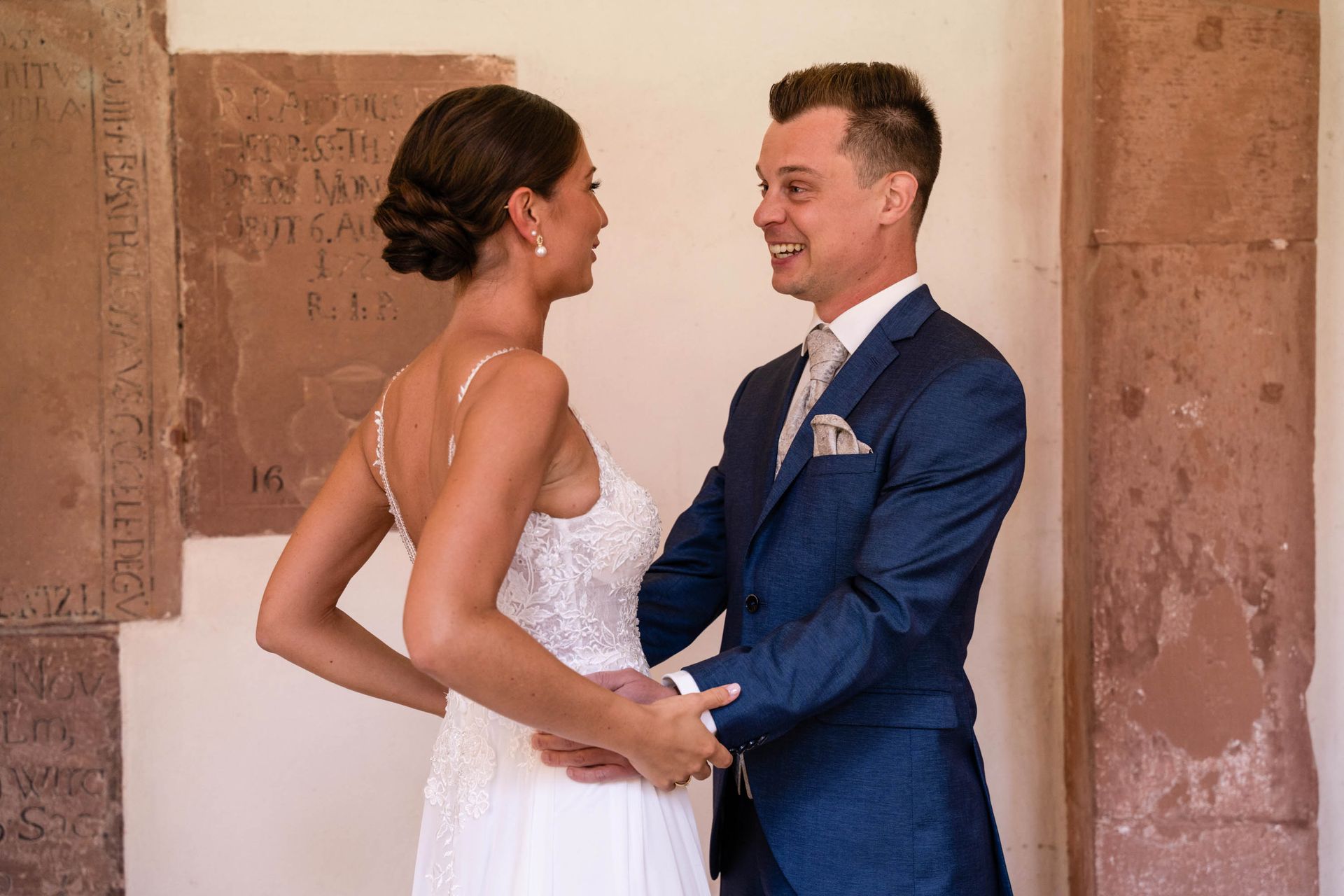 First Look im Kreuzgang Kloster Bronnbach, Bräutigam schaut Braut an und lächelt.